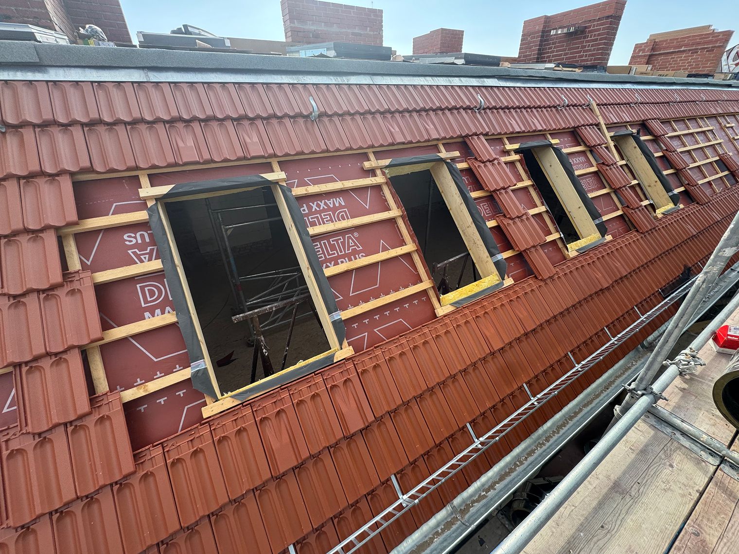 Dachsanierungsarbeiten mit offenen Fenstern und roten Ziegeln.