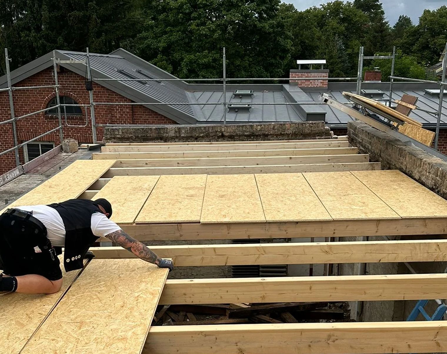 Arbeiter verlegt Holzplatten auf dem Dach