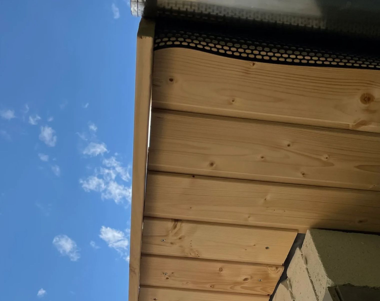 Sicht auf die Unterseite einer Holzverkleidung mit blauem Himmel