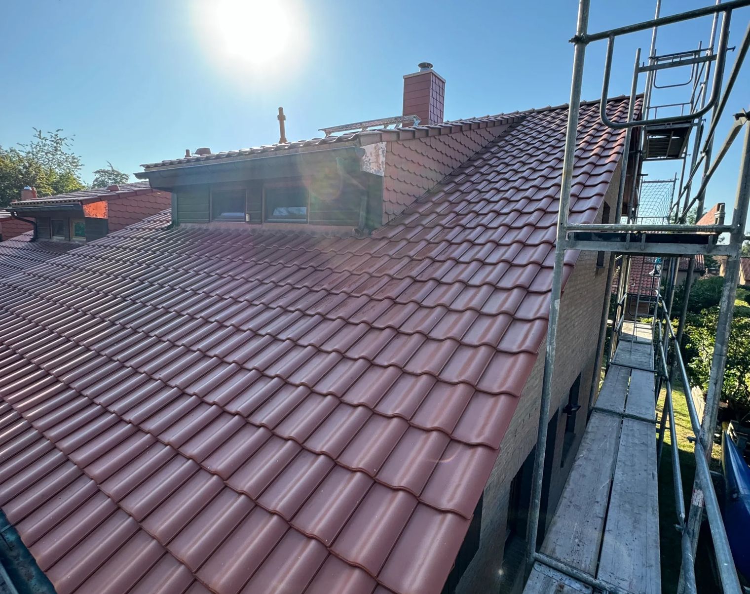 Sicht auf ein Dach mit roten Ziegeln und Sonnenlicht